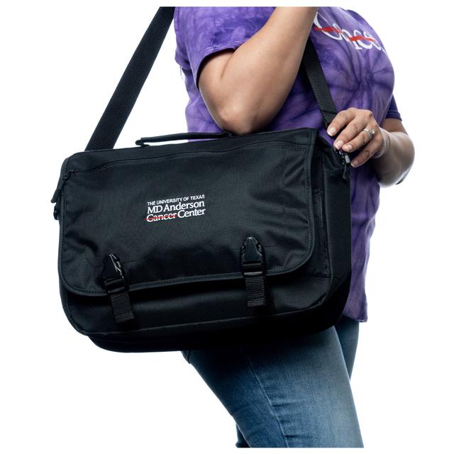 MD Anderson employee holding a black messenger briefcase featuring the white MD Anderson logo displayed on the front.