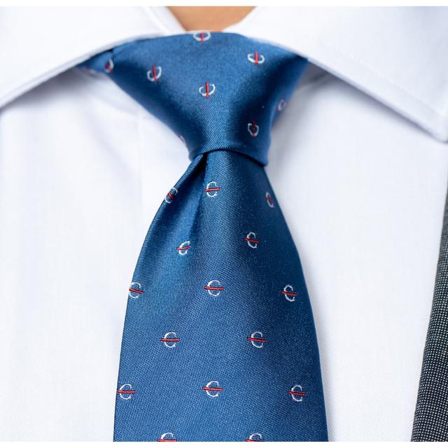 Close-up image of blue silk tie with the white strikethrough "C" pattern.